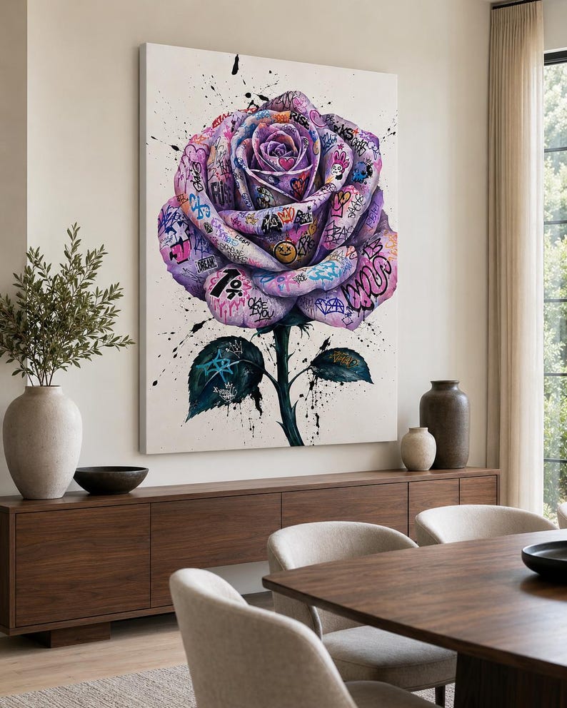 Puede incluir: Un gran cuadro rectangular de pared que muestra una rosa morada central cubierta de coloridos grafitis, etiquetas, s&iacute;mbolos y salpicaduras. La rosa tiene un tallo verde oscuro y dos hojas sobre un fondo blanco con gotas de pintura negra.