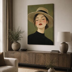 May include: A vertical canvas wall art print featuring a portrait of a person with closed eyes, wearing a wide-brimmed beige hat with a black band and a black high-neck top. The subject has red lipstick and rosy cheeks, set against a muted olive green background.