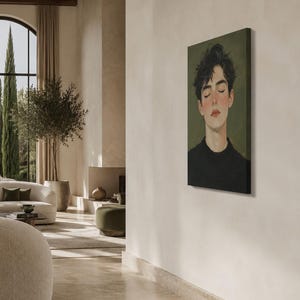 May include: A rectangular canvas wall art print featuring a portrait of a person with dark, messy hair and closed eyes. The subject has a fair complexion with rosy cheeks and wears a black crew-neck shirt against a muted olive green background.