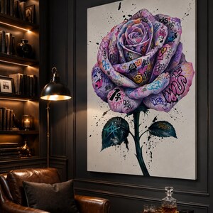Puede incluir: Un gran cuadro rectangular sobre lienzo que muestra una &uacute;nica rosa morada de gran tama&ntilde;o. Los p&eacute;talos est&aacute;n cubiertos con varios grafitis, s&iacute;mbolos y textos coloridos, incluida la palabra RISE. Salpicaduras de pintura negra acent&uacute;an la flor.