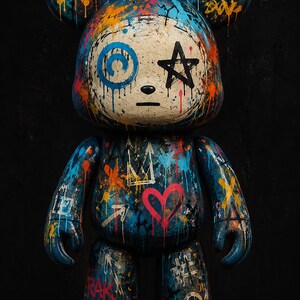 Op de afbeelding: Een beer-vormig verzamelfiguur met een cr&egrave;mekleurig gezicht en een blauw lichaam bedekt met levendige graffiti-stijl verfspatten. Het ontwerp bevat handgetekende symbolen zoals een zwarte ster, een roze hart, kronen en pijlen in oranje en blauw.