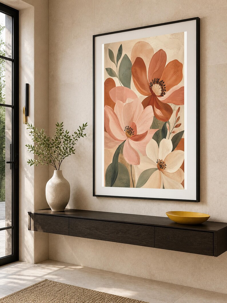 Puede incluir: Una impresi&oacute;n de arte mural vertical enmarcada que presenta una ilustraci&oacute;n bot&aacute;nica de flores grandes en tonos terracota, rosa suave y crema, acentuadas por hojas de color verde apagado, en un marco negro fino sobre una pared neutra.
