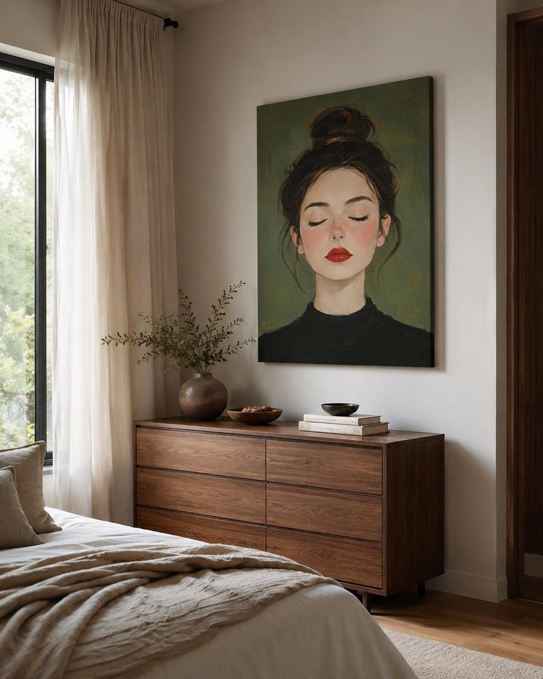 Puede incluir: Un lienzo rectangular de arte mural que presenta el retrato de una persona con cabello oscuro recogido en un mo&ntilde;o alto, ojos cerrados y labios de color rojo brillante, sobre un fondo verde oliva s&oacute;lido, enmarcado en una pared blanca.