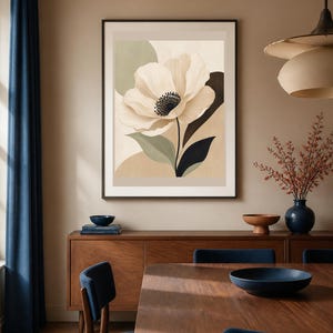 K&ouml;nnte beinhalten: Ein gerahmter Kunstdruck mit einer gro&szlig;en, cremefarbenen Blume mit dunkler Mitte vor einem Hintergrund aus abstrakten Formen in Beige, Salbeigr&uuml;n und Dunkelbraun. Das Kunstwerk befindet sich in einem d&uuml;nnen schwarzen Rahmen an einer beigen Wand.