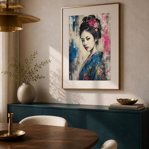 Puede incluir: Una l&aacute;mina de arte enmarcada que muestra el retrato de una persona con un elaborado peinado oscuro adornado con flores rosas, vistiendo un kimono azul estampado, sobre un fondo texturizado con trazos de pintura verticales azules y rosas.