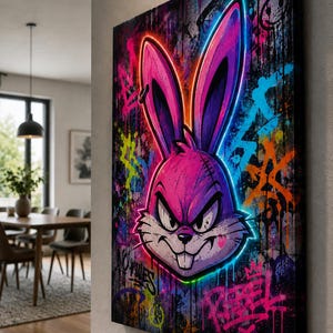Peut inclure: Une toile murale rectangulaire repr&eacute;sentant une illustration de style graffiti d'une t&ecirc;te de lapin violette avec des contours n&eacute;on lumineux. Le fond est une surface sombre et textur&eacute;e couverte d'&eacute;claboussures de peinture et du mot Rebel.