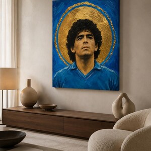 Puede incluir: Un cuadro rectangular sobre lienzo que muestra el retrato de un hombre de pelo rizado oscuro con una camisa de cuello azul. Detr&aacute;s de la figura hay un gran halo circular dorado y texturizado sobre un fondo azul vibrante con pinceladas visibles.