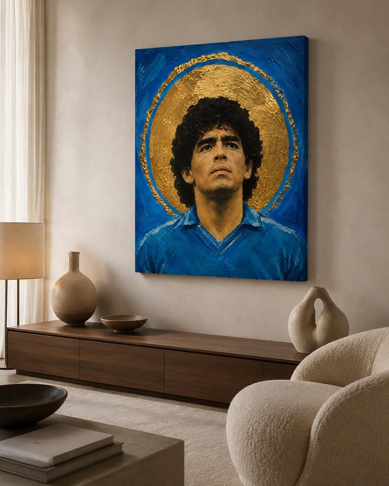 Puede incluir: Un cuadro rectangular sobre lienzo que muestra el retrato de un hombre de pelo rizado oscuro con una camisa de cuello azul. Detr&aacute;s de la figura hay un gran halo circular dorado y texturizado sobre un fondo azul vibrante con pinceladas visibles.