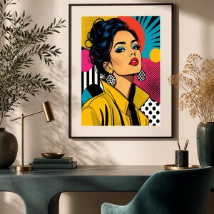May include: A framed pop art print featuring a stylized illustration of a person with dark hair in an updo, wearing a yellow jacket and large polka-dot earrings. The background consists of vibrant geometric shapes, including red, blue, and yellow circles, black stripes, and white dots on a pink field.