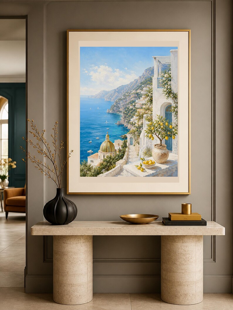 May include: A framed wall art print depicting a coastal Mediterranean scene with a blue sea, a golden domed church, white buildings, and a potted lemon tree. The artwork is displayed in a thin gold frame with a wide cream-colored matting border.
