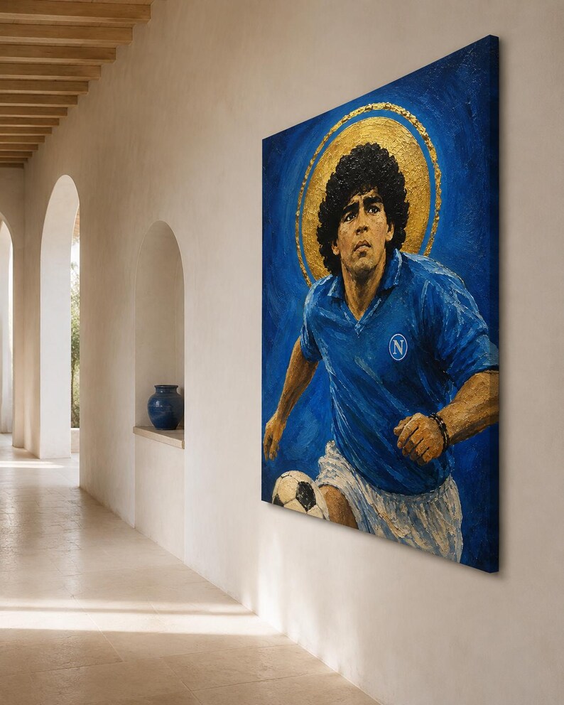 May include: A rectangular canvas painting depicting a soccer player with dark curly hair wearing a blue jersey with a white N logo and white shorts. The player is positioned against a deep blue background with a prominent gold circular halo behind the head.
