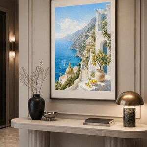 May include: A framed vertical wall art print depicting a coastal Mediterranean scene with a blue sea, a domed church, white buildings, and a potted lemon tree on a terrace. The painting features bright yellow lemons, green foliage, and a clear sky.