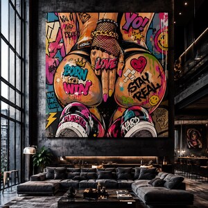 Op de afbeelding: Een groot vierkant wandkunstwerk met levendige graffiti-stijl straatkunst. De compositie toont een hand met een visnet-handschoen en gouden ketting, omringd door kleurrijke teksten zoals BORN TO WIN, LOVE en STAY REAL, met sneakers.