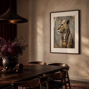 May include: A framed wall art print featuring a stylized lioness with intricate gold and brown geometric patterns on her fur, set against a dark gray background with gold leaf accents, displayed in a thin dark frame on a textured wall.