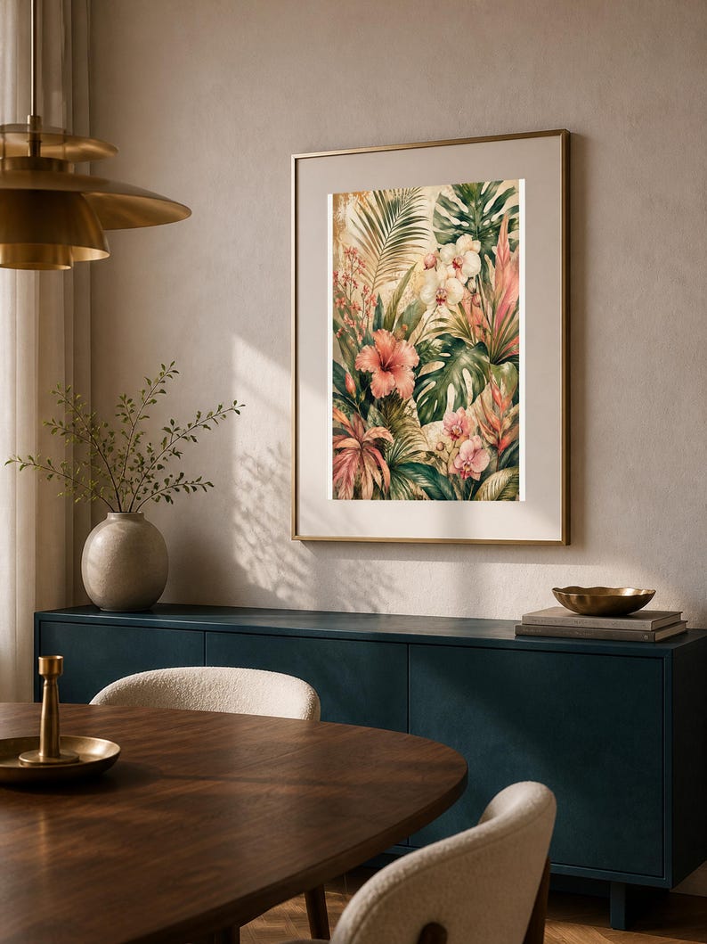 May include: A framed wall art print featuring a botanical illustration of tropical foliage, including large green monstera leaves, pink hibiscus flowers, and white orchids, set against a warm, muted background with golden highlights.