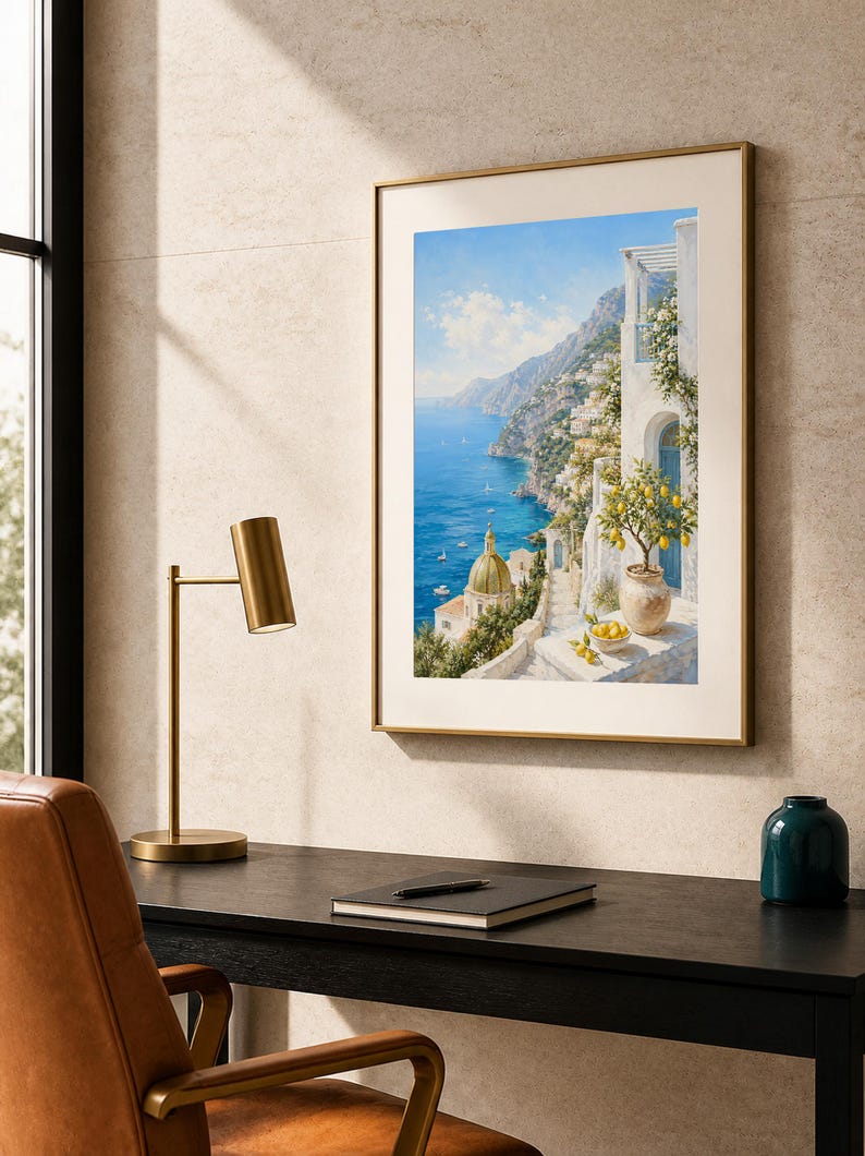 May include: A framed wall art print depicting a coastal Mediterranean scene with white buildings, a golden domed church, a blue sea, and a potted lemon tree in the foreground. The artwork is displayed in a thin gold frame on a textured wall.
