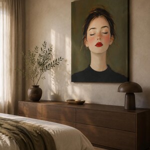 Puede incluir: Una gran impresi&oacute;n art&iacute;stica rectangular que presenta el retrato de una persona con los ojos cerrados, mejillas sonrosadas y labios rojos brillantes, vistiendo una prenda negra sobre un fondo verde oliva apagado. La obra se exhibe en un dormitorio.
