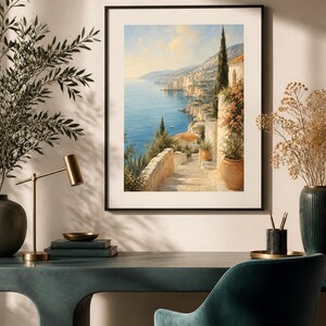 Puede incluir: Una impresi&oacute;n de arte mural vertical enmarcada que representa un paisaje costero mediterr&aacute;neo con una escalera de piedra que conduce hacia un mar azul, con macetas de terracota, cipreses y edificios claros bajo un cielo soleado.