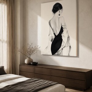 May include: A large square wall art print featuring a black and white illustration of a person seen from behind. The figure wears a black slip dress with thin straps and a draped white garment over the shoulders, with dark hair styled in a bun.