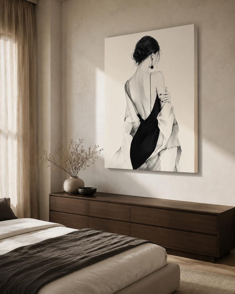 May include: A large square wall art print featuring a black and white illustration of a person seen from behind. The figure wears a black slip dress with thin straps and a draped white garment over the shoulders, with dark hair styled in a bun.