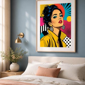 May include: A framed pop art print featuring a stylized illustration of a person with dark hair in an updo, wearing a yellow jacket and large patterned earrings. The background incorporates vibrant colors, geometric shapes, and dot patterns.