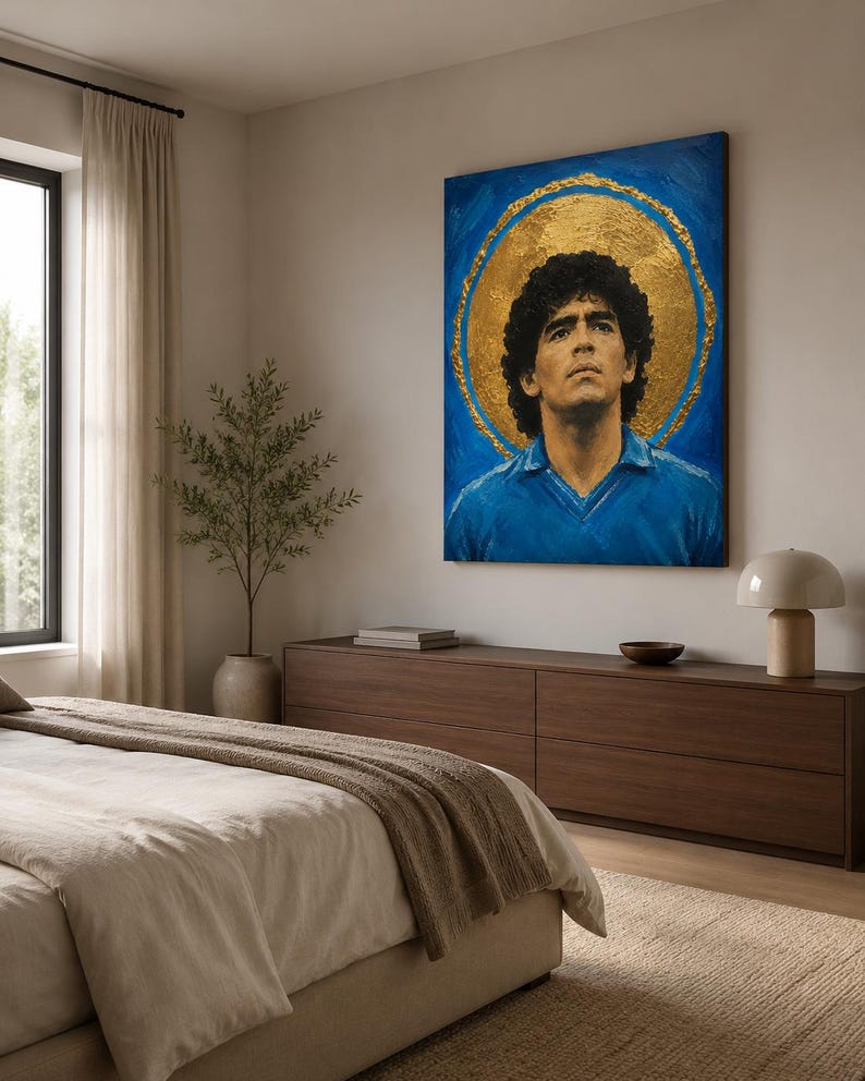 Puede incluir: Una pieza de arte mural rectangular que presenta el retrato de un hombre con cabello oscuro y rizado que viste una camisa azul con cuello. La figura se sit&uacute;a sobre un fondo azul vibrante con un gran halo circular dorado y texturizado.