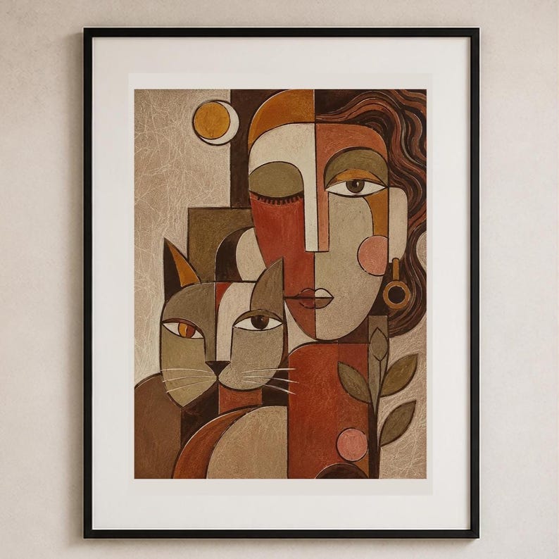 May include: A framed wall art print featuring a stylized portrait of a person and a cat. The composition uses a palette of terracotta, beige, and brown tones with geometric shapes. A small circular moon and a plant stem are visible in the artwork.