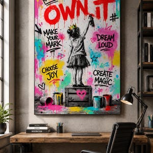 May include: A vertical wall art print featuring a black and white illustration of a child wearing a crown, standing on a wooden crate and spray painting the text OWN IT in red. The background is a vibrant graffiti collage with colorful paint splatters.