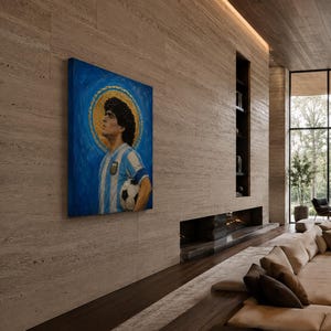 May include: A rectangular canvas painting featuring a portrait of a soccer player with curly dark hair, wearing a blue and white striped jersey, holding a soccer ball, set against a blue background with a prominent gold circular halo behind the head.