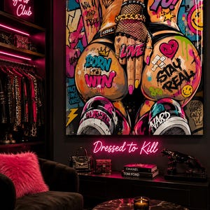 Op de afbeelding: Een groot vierkant wandkunstwerk met levendige graffiti-stijl straatkunst. Het kunstwerk toont de onderrug en handen van een persoon met visnet-handschoenen, versierd met kleurrijke teksten zoals BORN TO WIN, LOVE en STAY REAL, plus diverse iconen.