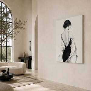 May include: A large rectangular wall art print featuring a black and white illustration of a figure seen from behind. The figure wears a black dress with thin straps and a draped light-colored garment over the shoulders, with dark hair styled up.