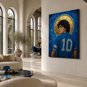 May include: A rectangular wall art piece featuring a portrait of a person with dark curly hair wearing a blue jersey with the number 10 on the back. The figure is set against a textured blue background with a prominent circular gold leaf halo.