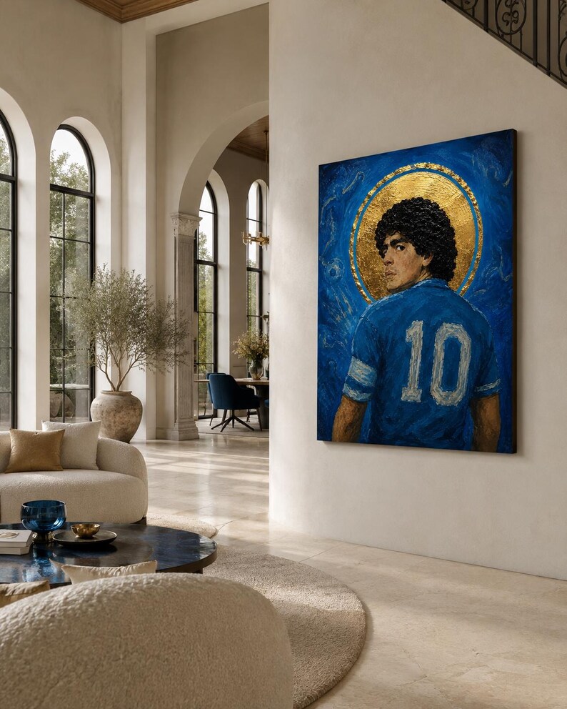 May include: A rectangular wall art piece featuring a portrait of a person with dark curly hair wearing a blue jersey with the number 10 on the back. The figure is set against a textured blue background with a prominent circular gold leaf halo.