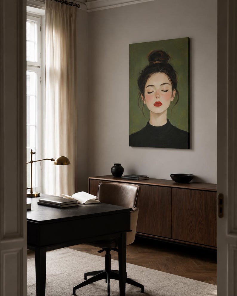 Puede incluir: Un cuadro rectangular sobre lienzo que muestra el retrato de una persona con el cabello oscuro recogido en un mo&ntilde;o alto, ojos cerrados y labios de color rojo brillante, sobre un fondo verde oliva s&oacute;lido, expuesto en una oficina en casa.