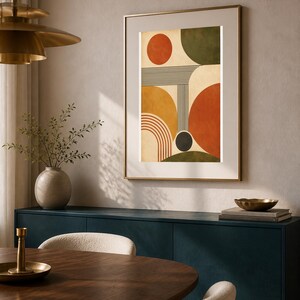Puede incluir: Una impresi&oacute;n de arte mural vertical enmarcada que presenta una composici&oacute;n abstracta de formas geom&eacute;tricas, incluyendo c&iacute;rculos, semic&iacute;rculos y l&iacute;neas paralelas en tonos naranja quemado, amarillo mostaza, verde oliva y crema.