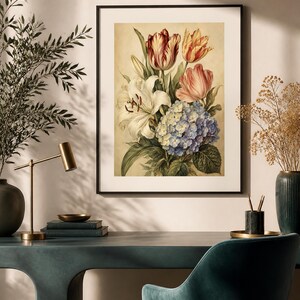 May include: A framed botanical wall art print featuring a bouquet of flowers including a large white lily, a blue hydrangea, and red and yellow tulips against a cream background, displayed in a thin black frame on a light-colored wall.
