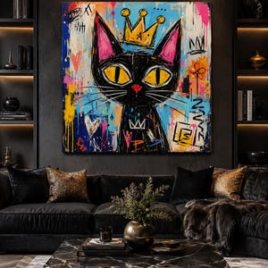 Pode incluir: Uma pintura em tela quadrada apresentando um gato preto estilizado com grandes olhos amarelos e uma coroa dourada. O fundo &eacute; uma mistura vibrante de respingos de tinta azul, rosa e amarela com rabiscos pretos, cora&ccedil;&otilde;es e coroas.