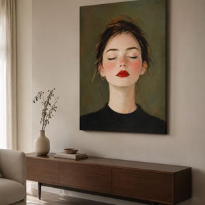 Puede incluir: Una impresi&oacute;n de arte mural rectangular que muestra el retrato de una persona con los ojos cerrados, mejillas sonrosadas y labios rojos brillantes. El sujeto tiene el cabello oscuro recogido y viste una prenda negra sobre un fondo verde oliva.
