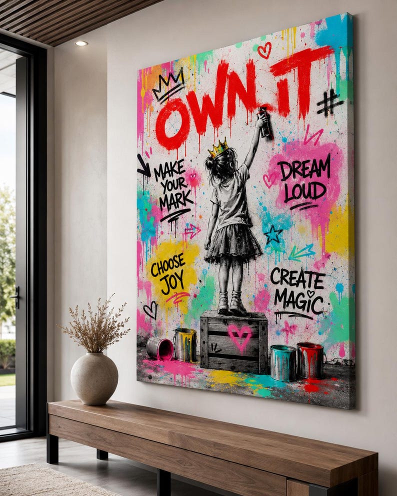 May include: A rectangular canvas wall art piece featuring a black and white illustration of a child wearing a crown, standing on a wooden crate and spray painting the text OWN IT in red. The background is a vibrant splatter of neon paint colors.