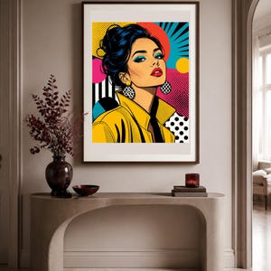 May include: A framed pop art print featuring a stylized illustration of a person with dark hair in an updo, wearing a yellow jacket and large circular earrings. The background incorporates vibrant colors, geometric shapes, and black and white dots.