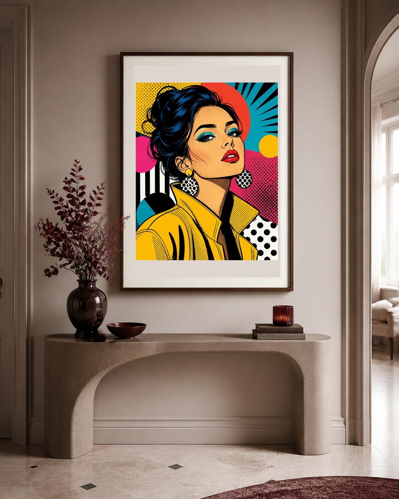 May include: A framed pop art print featuring a stylized illustration of a person with dark hair in an updo, wearing a yellow jacket and large circular earrings. The background incorporates vibrant colors, geometric shapes, and black and white dots.