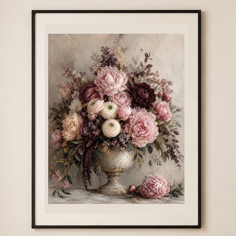 May include: A framed wall art print featuring a floral arrangement in a stone-colored pedestal vase. The bouquet includes large pink and dark burgundy peonies, white ranunculus, and purple sprigs, with one pink peony resting on the surface.