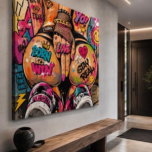 Op de afbeelding: Een rechthoekig canvas wandkunstwerk met levendige graffiti-stijl street art. Het kunstwerk toont gedurfde teksten waaronder BORN TO WIN, STAY REAL, LOVE en YO, naast kleurrijke verfspatten, visnetpatronen en gouden kettingdetails.
