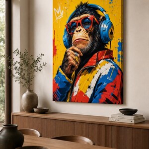 May include: A rectangular canvas wall art print featuring a chimpanzee wearing blue headphones, red-rimmed glasses, and a gold ring on its finger. The chimpanzee wears a colorful jacket with red, blue, and yellow paint splatters on a yellow background.
