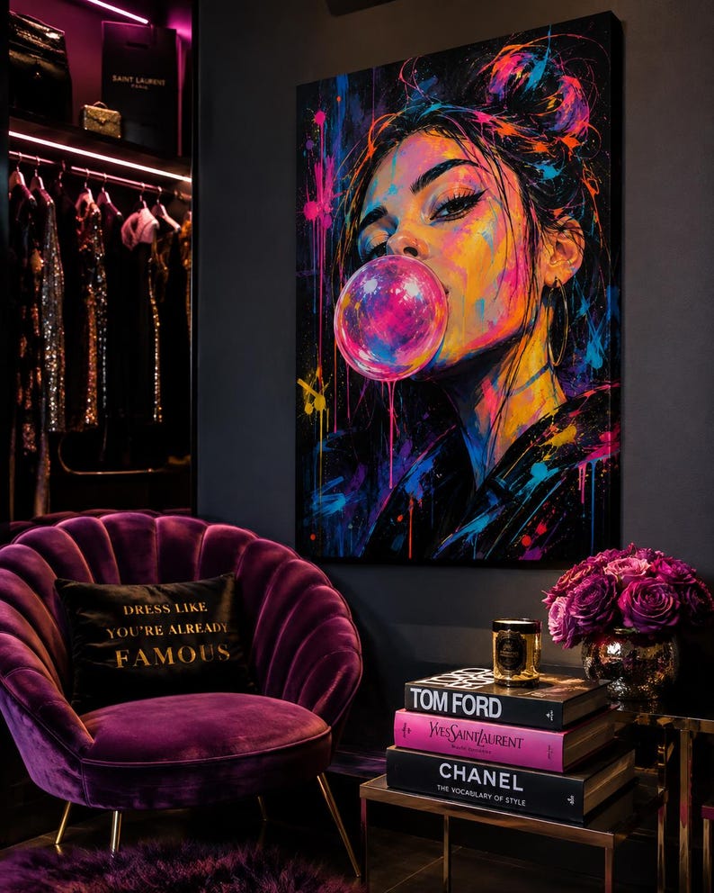 Puede incluir: Un lienzo vibrante que muestra a una persona soplando una burbuja de chicle rosa, con salpicaduras de pintura ne&oacute;n en azul, amarillo y rosa. La obra se exhibe en una habitaci&oacute;n con un sill&oacute;n de terciopelo morado y un coj&iacute;n negro con texto dorado.