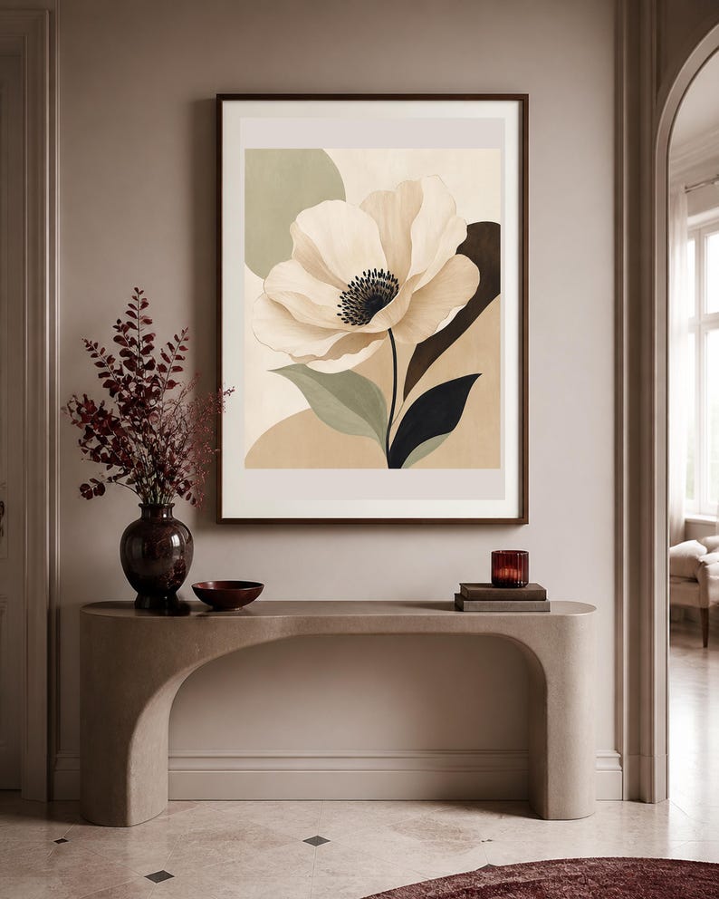 K&ouml;nnte beinhalten: Ein gerahmter Kunstdruck mit einer gro&szlig;en, stilisierten cremefarbenen Blume mit dunkler Mitte, vor abstrakten Formen in gedeckten Salbeigr&uuml;n-, Beige- und Dunkelbraunt&ouml;nen. Das Kunstwerk befindet sich in einem dunkelbraunen Rahmen an der Wand.