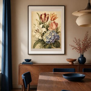 May include: A framed wall art print featuring a botanical illustration of a floral bouquet. The arrangement includes a white lily, a blue hydrangea, and red and yellow tulips with green leaves, all set against a light beige background.