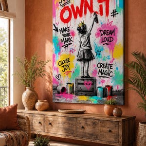 May include: A rectangular wall art canvas featuring a black and white illustration of a child wearing a crown and standing on a crate, painting the red text OWN IT. The background is filled with colorful graffiti splashes and motivational phrases.