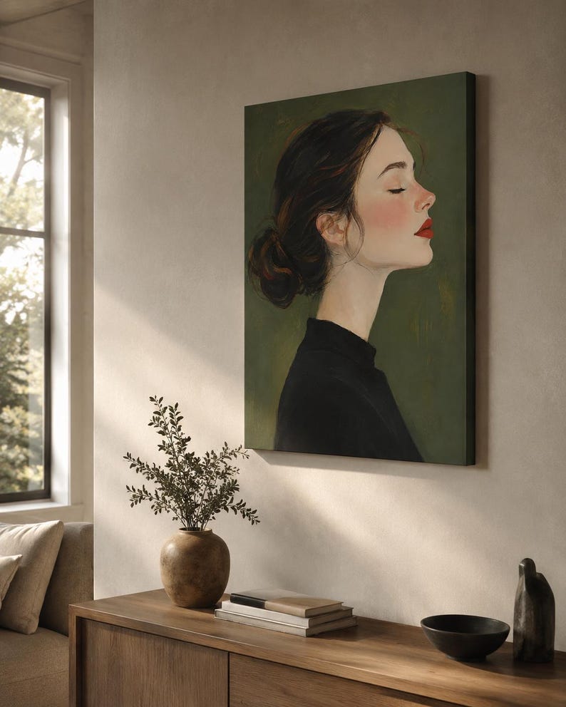 Puede incluir: Una impresi&oacute;n de arte mural rectangular que presenta un retrato de perfil de una persona con cabello oscuro recogido en un mo&ntilde;o, vistiendo una prenda negra sobre un fondo verde oliva oscuro. Tiene los ojos cerrados, mejillas rosadas y labios rojos.