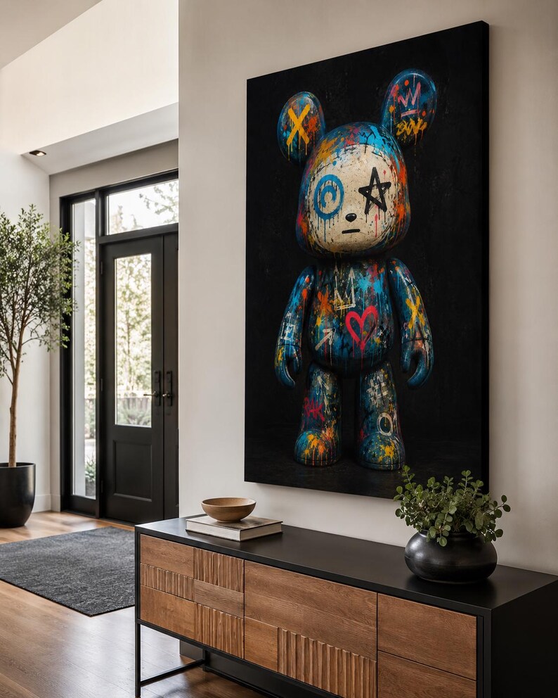 Op de afbeelding: Een groot rechthoekig wandkunstwerk met een gestileerde berenfiguur tegen een effen zwarte achtergrond. De beer is bedekt met levendige graffiti-achtige verfspatten, waaronder blauw, oranje en rood, met symbolen zoals een hart en een ster.